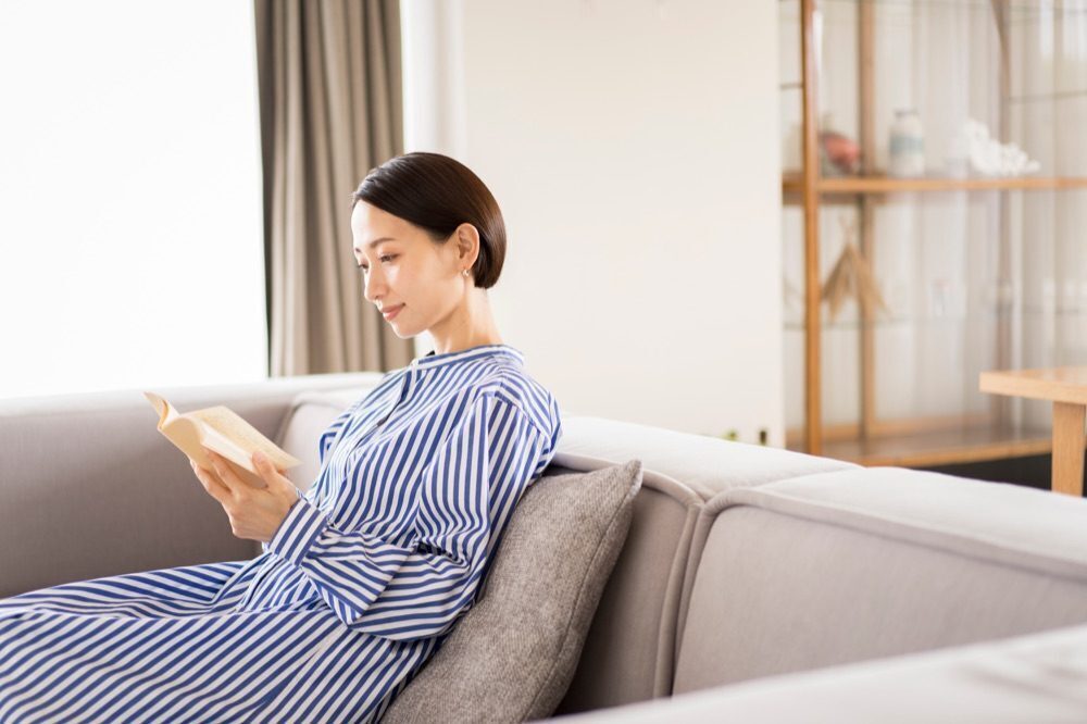 ソファーで本を読む女性